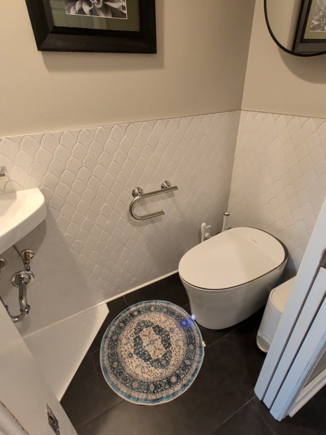 Modern powder room remodel with corner sink, textured white wall tile, dark floor tile, and framed wall art