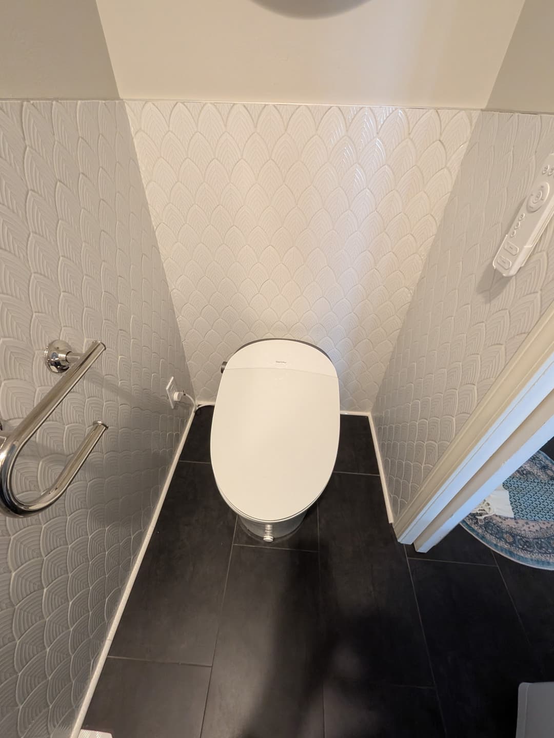 Compact powder room sink installation with textured white tile walls, chrome fixtures, and modern wall mirror